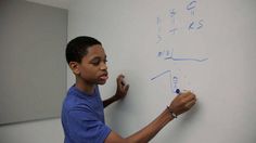 a young boy writing on a white board