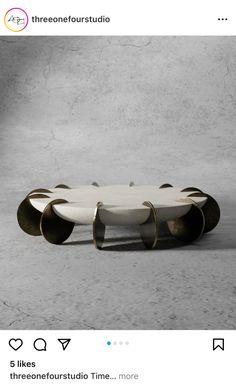 a white and gold coffee table sitting on top of a cement floor next to a wall