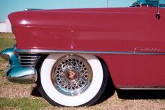 an old red and white car is parked in the grass with it's wheels