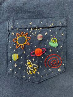 an embroidered pocket on the back of a denim shirt with space and planets in it