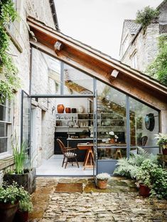 an outdoor dining area in the middle of a stone building with lots of plants and potted plants