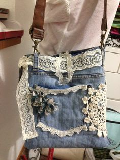 a woman is holding a purse made out of old jeans and lace, with her hands in the pockets