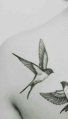 the back of a woman's shoulder with two birds flying above her and one bird on