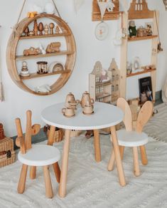 two children's wooden chairs and table in a room with shelves on the wall