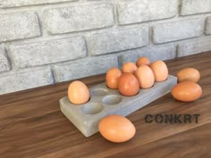 several eggs are placed in an egg tray on a table next to a brick wall