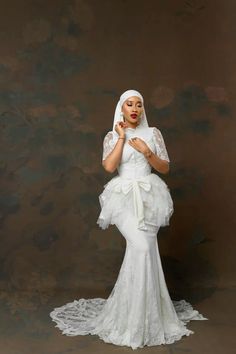 a woman in a white dress and veil posing for the camera with her hands on her lips