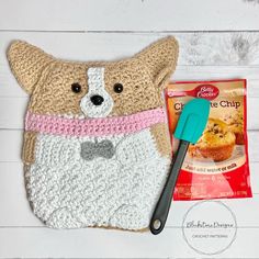 a crocheted dog pot holder next to a bag of chips and a plastic spatula