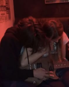 two people sitting on a couch playing guitar