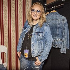 a woman standing next to a pair of jean jackets