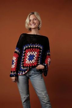 a woman is smiling and wearing a sweater made out of crocheted grannys