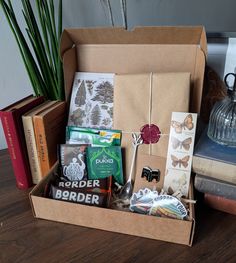 an open box filled with assorted items sitting on top of a wooden table next to books