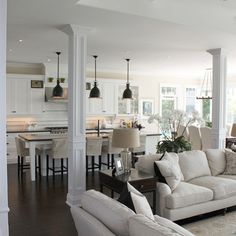 a living room filled with furniture next to a kitchen and dining room table in front of an open floor plan