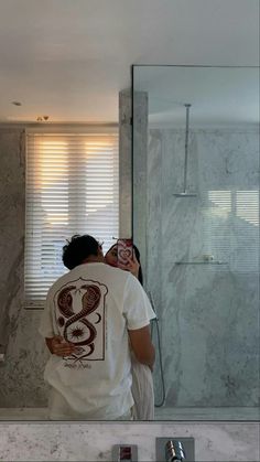 a man taking a selfie in front of a bathroom mirror with his phone up to his face