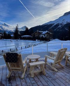 three wooden chairs sitting on top of a snow covered deck