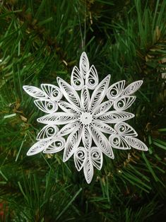 a paper snowflake ornament hanging from a christmas tree