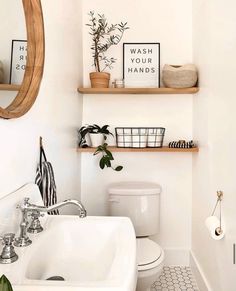 a white bathroom with black and white tile flooring, shelving above the toilet