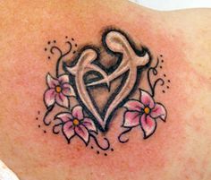 a tattoo on the back of a woman's shoulder with pink flowers and hearts