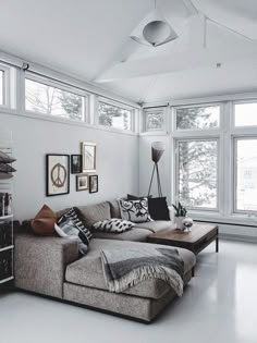 a living room filled with lots of furniture next to large windows on top of a white floor