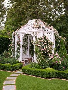 a white gazebo surrounded by greenery and flowers