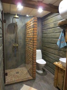 a bathroom with a toilet, sink and shower in it's stall area next to a wood paneled wall