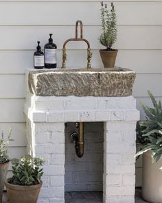 a white brick sink sitting on top of a counter next to potted plants