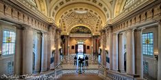 two people are standing in the middle of a large hall with marble columns and arches