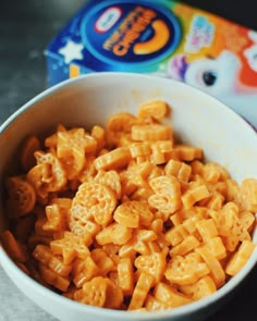 a white bowl filled with macaroni and cheese next to a box of cereal