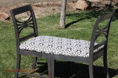 a chair sitting on top of a grass covered field next to a tree and rocks