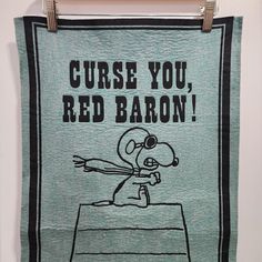 a towel hanging on a wall that says curse you, red baron with a cartoon character holding a baseball bat