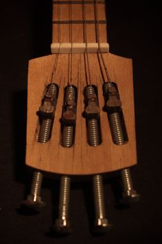 four screws are attached to the back of an acoustic guitar's frets