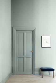 an empty room with a blue bench in the corner and a white wall behind it