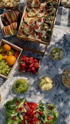 an assortment of fruits and vegetables on a table with breads, salads, and croissants