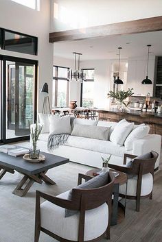 a living room filled with white furniture and lots of glass doors leading to an open kitchen