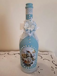 a blue bottle decorated with flowers and pearls on a doily tablecloth covered table