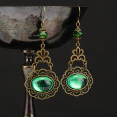 Marquesa Questa Renaissance Earrings - Antique Bronze & Emerald Green Some people were born to fade into the grey of the day, but you were meant to shine and shimmer like royalty. These breathtaking Marquesa Questa Renaissance earrings are the best of beautiful and bold. Each earring features a dazzling emerald green oval gem mounted in beautiful antique bronze. Just above is a gorgeous floral filigree and shimmering emerald green crystal. Wear these shimmering earrings alone or pair them with M Teardrop Pearl Earrings, Emerald Green Crystal, Bronze Green, Floral Filigree, Golden Amber, Light Sapphire, Green Oval, Fan Earrings, Green Gems