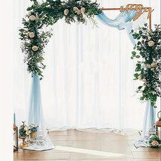 an arch decorated with flowers and greenery for a wedding ceremony in front of a window