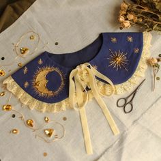 a blue and white bib with gold stars on it next to scissors, flowers and other accessories