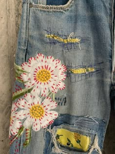 an old pair of jeans with flowers painted on the side and torn in to them