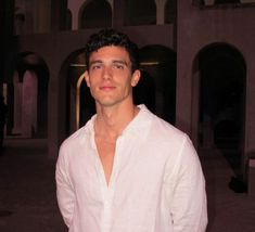 a man standing in front of a building at night with his hands in his pockets