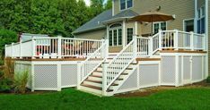 a deck with an umbrella and steps leading up to the back of a house on a sunny day