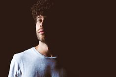 a man with curly hair standing in the dark