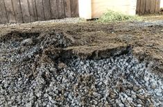 a pile of dirt next to a wooden fence