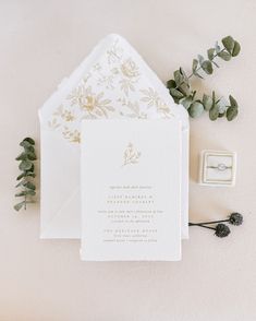 the wedding stationery is laid out with greenery