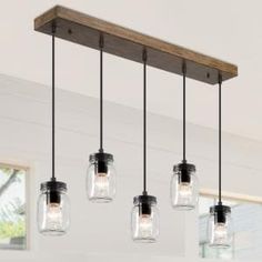 four mason jar lights hanging from a wooden beam in a kitchen with white walls and windows