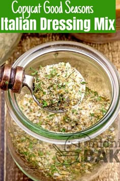 a glass jar filled with food on top of a wooden table next to a spoon