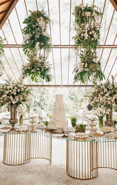 a table topped with lots of white flowers and greenery next to a tall cake