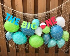 there are balloons that say the big one hanging from a string on a fence outside