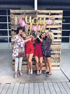 four women posing in front of a wooden sign that says happy new year on it