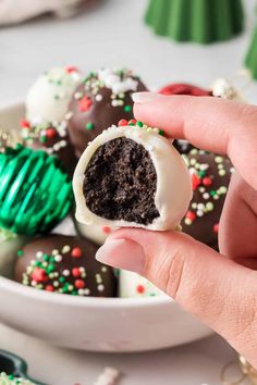 a hand holding a half eaten chocolate truffle with sprinkles on it