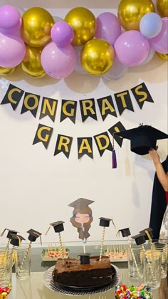 a graduation party with balloons and confetti on the wall, cake and decorations